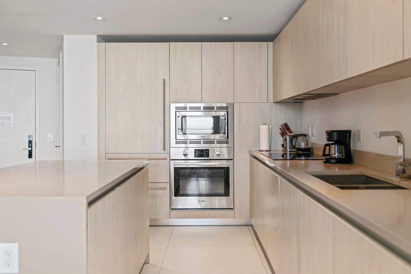 A modern kitchen with a Bosch microwave and oven, a coffee maker, and a sink.