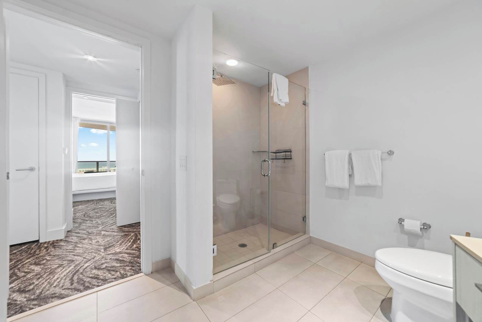 A modern bathroom with a glass shower enclosure, a toilet, and a sink.