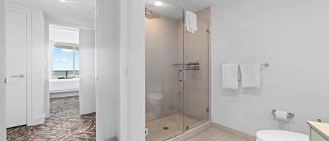 A modern bathroom with a glass shower enclosure, a toilet, and a sink.