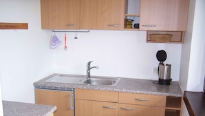 A kitchen with a sink, wooden cabinets, a coffee maker, and a hanging utensil rack. - Studio 'Unterschütz' with Mountain View, Private Terrace and Wi-Fi (Ettenheim)
