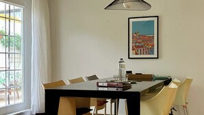 A dining area with a black table, beige chairs, a hanging light fixture, and a framed painting on the wall. - Casa Belavista near Lisbon (Palmela)