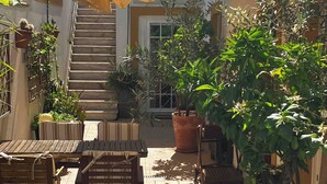 An outdoor patio area with a wooden table and chairs, potted plants, and a staircase leading to an upper level. - Casa Belavista near Lisbon (Palmela)