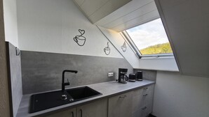A modern kitchen with a black sink, a coffee maker, and a window with a view of greenery. - Holiday Apartment 'Andreas' with Mountain View and Wi-Fi (Sankt Blasien)