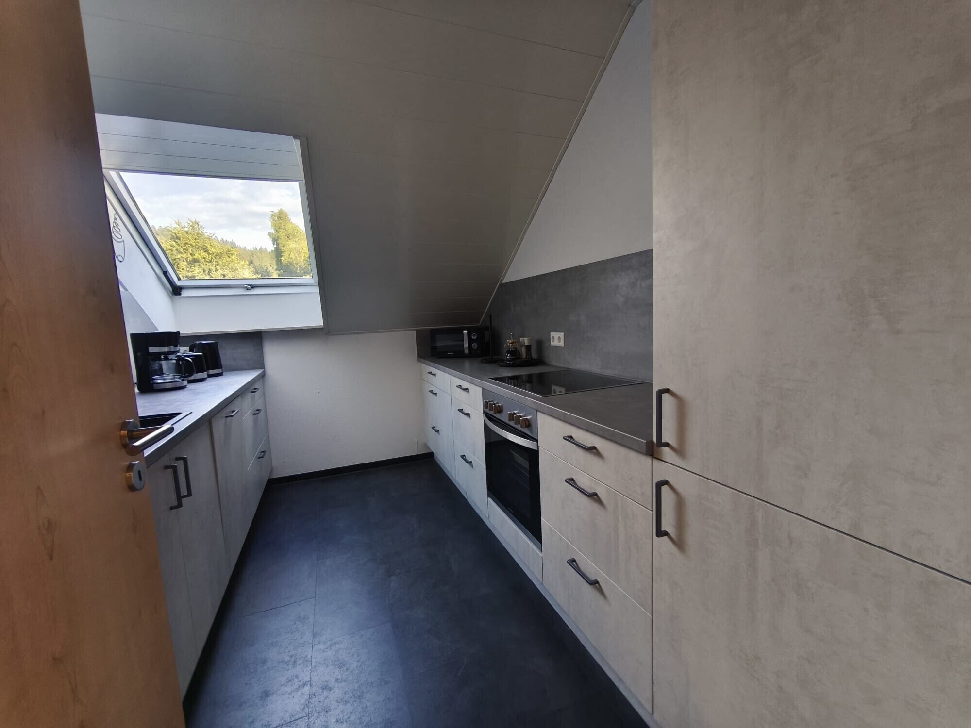 A compact kitchen with a skylight, a built-in oven, and a microwave.