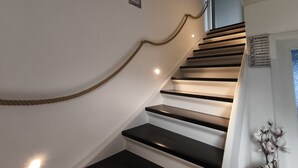 A staircase with a wooden handrail and black steps, leading to a door with a heart symbol. - Holiday Apartment 'Andreas' with Mountain View and Wi-Fi (Sankt Blasien)
