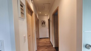 A hallway with wooden flooring, white walls, and doors with labels. - Holiday Apartment 'Andreas' with Mountain View and Wi-Fi (Sankt Blasien)