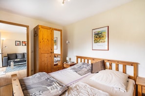 A bedroom with a wooden bed, a nightstand, a wardrobe, a mirror, and a framed picture on the wall.