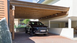 Un VUS noir était garé sous une pergola en bois, dans un espace de stationnement couvert dont le sol était en briques.