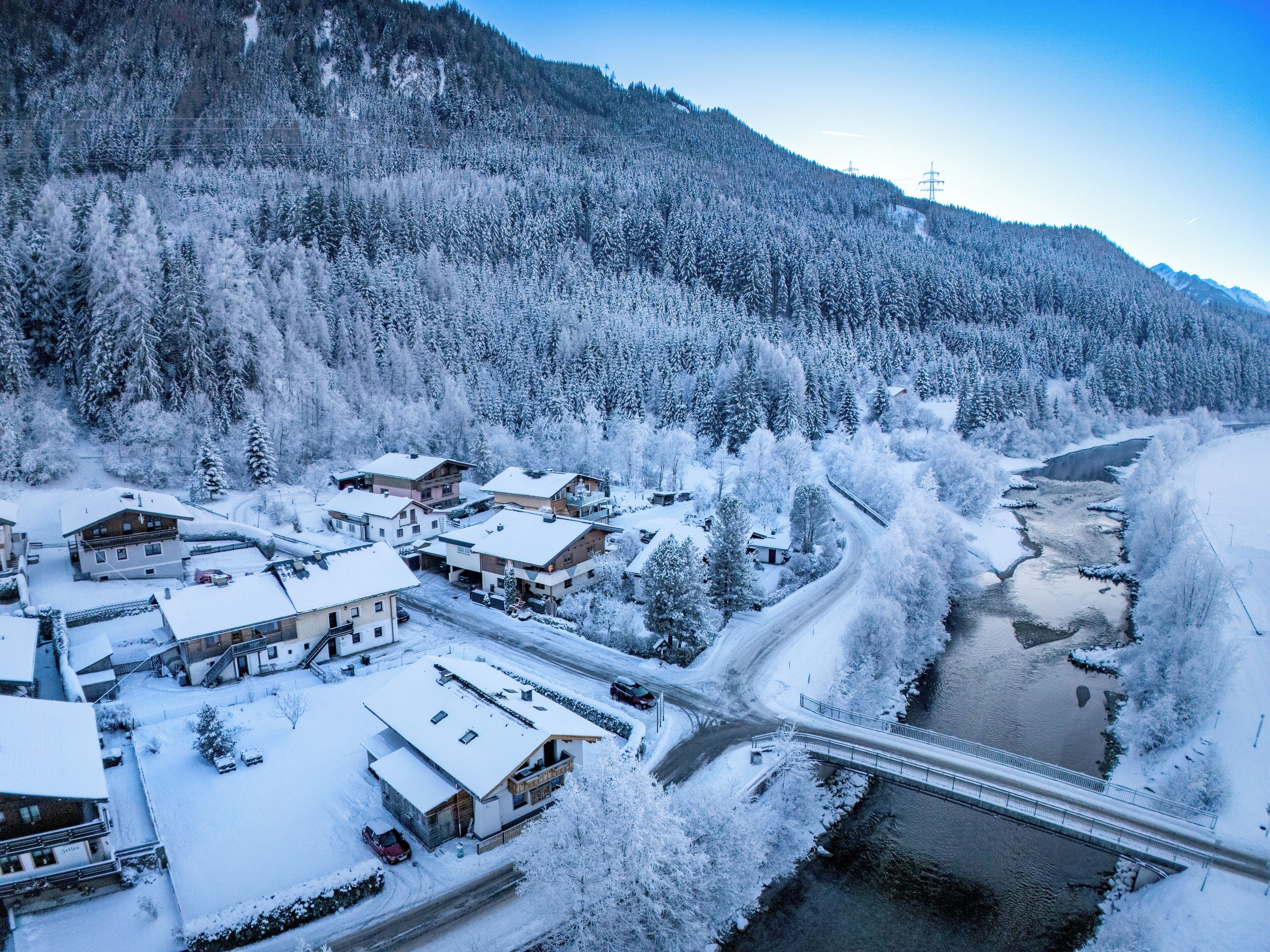Un village enneigé avec des maisons, un pont et une rivière.