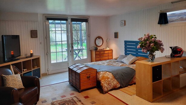 Een slaapkamer met een bed, een dressoir, een televisie en uitzicht door de deur.