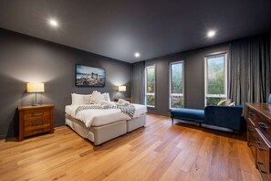 Un dormitorio moderno con una cama grande, mesitas de noche, un sofá y un aparador.
