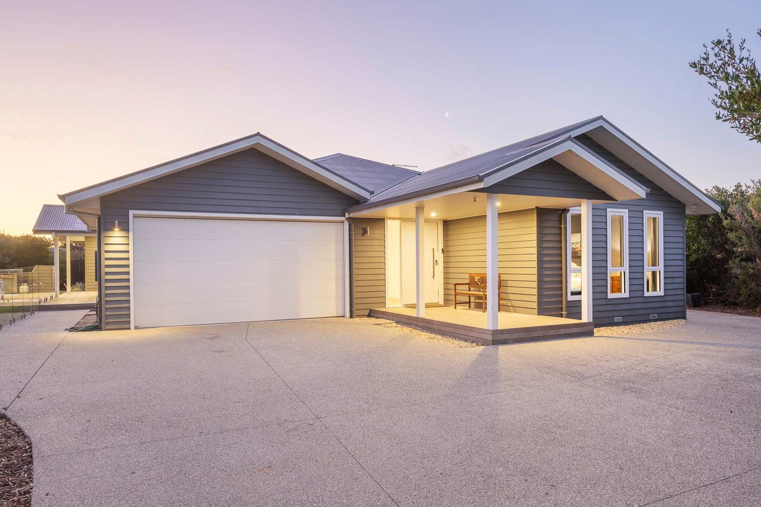 A modern two-story house with a garage, a covered porch, and a landscaped driveway.