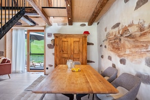 Un comedor con una mesa de madera, sillas y vistas al exterior.