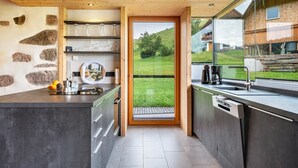 Una cocina moderna con pared de piedra, techo de madera y vistas a un paisaje verde.