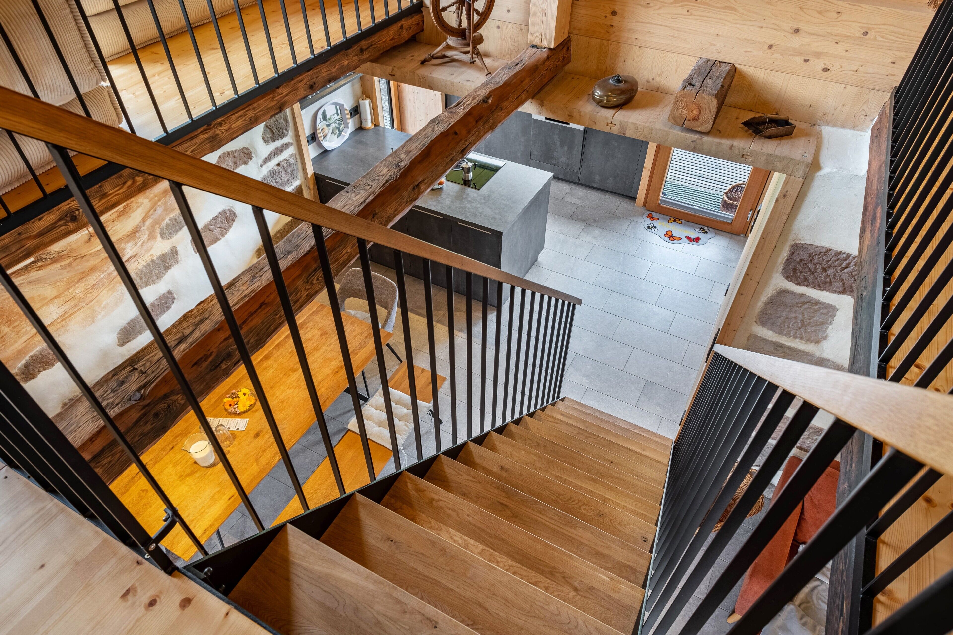 A wooden staircase with a metal railing leading to a living area with a sofa, coffee table, and a small table with a kettle.