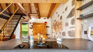 Una cocina moderna con estufa integrada, detalles de madera y una pared de piedra.