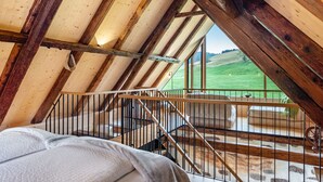 Un dormitorio con techo de madera, una cama, un ventanal y un balcón.