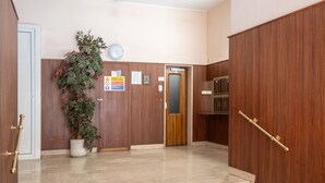 A hotel lobby with a wooden wall, a potted plant, a staircase, and a door. - Penthouse Seaview by Wonderful Italy (Sanremo)