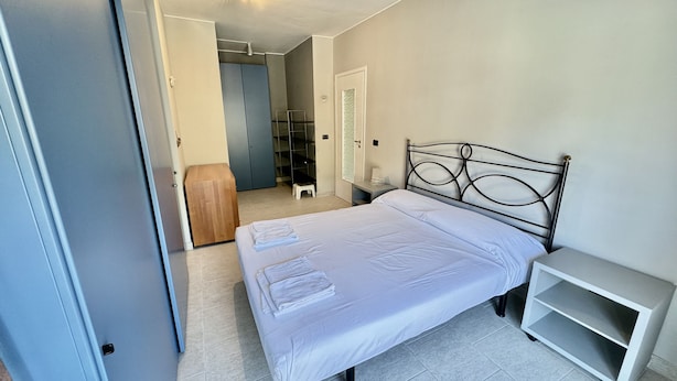 A bedroom with a bed, bedside table, and a wardrobe. - Penthouse Seaview by Wonderful Italy (Sanremo)