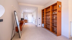 A hallway with a wooden bookshelf, a mirror, and a desk with a computer. - Penthouse Seaview by Wonderful Italy (Sanremo)