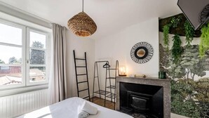 A hotel room with a bed, a fireplace, a woven light fixture, a ladder, and a wall mural. - Maison d'Or (Saint-Cyr-au-Mont-d'Or)