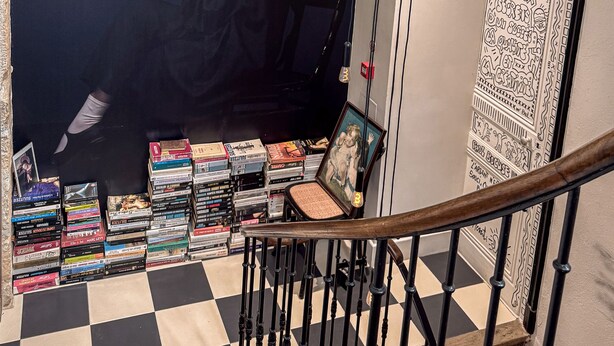 A staircase with a checkered floor, a wall with a framed picture, and a collection of books and DVDs on the floor. - Maison d'Or (Saint-Cyr-au-Mont-d'Or)