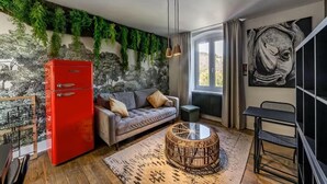 A modern living room with a red refrigerator, grey sofa, and a round wicker coffee table. - Maison d'Or (Saint-Cyr-au-Mont-d'Or)