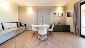 Un salon moderne comprenant un canapé, une table à manger, des chaises, un meuble et un téléviseur.