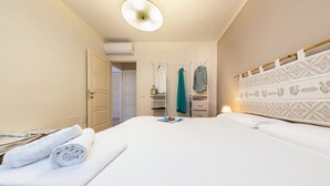 Une chambre d’hôtel avec un lit bien fait, une armoire, un miroir et une lampe de chevet.