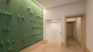 Un corridoio con una parete verde a texture, una porta bianca e un pavimento piastrellato.