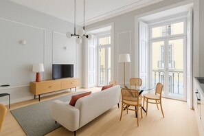 A modern living room with a sofa, TV, and dining area with chairs. - 2bed flat with Balcony in Central Lisbon (Lisbon)