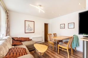 Una sala de estar con sofá, sillas, una mesa y un televisor.