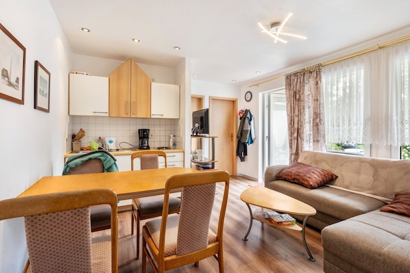 Un espacio habitable compacto con comedor, kitchenette y un sofá con vistas.