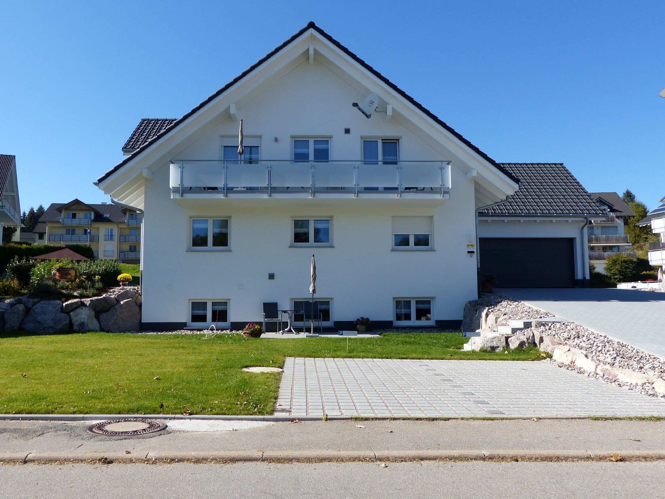 Un immeuble résidentiel de deux étages doté d’un balcon, d’un garage et d’une allée pavée.