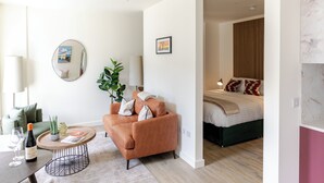 Un salon moderne avec un canapé, une table basse et un lit dans la pièce adjacente.
