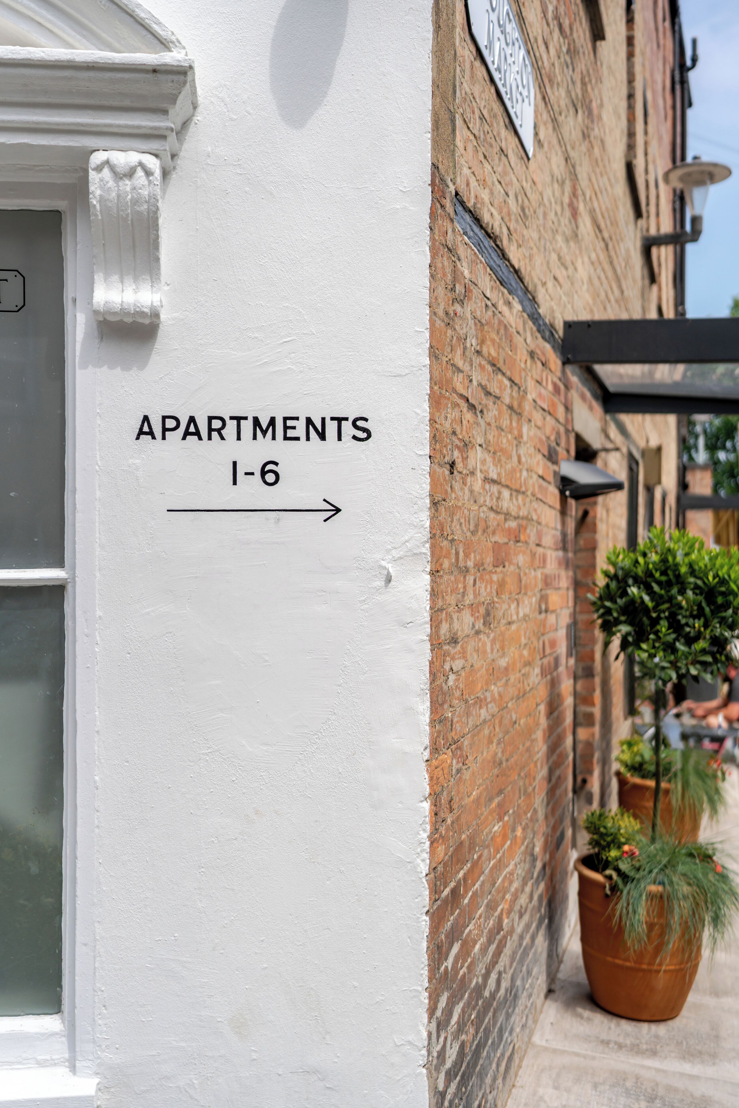 A white wall with a sign indicating 'Apartments 1-6'.