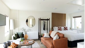 Une chambre d’hôtel moderne, équipée d’un lit, d’un canapé, d’une table basse et d’une petite plante.