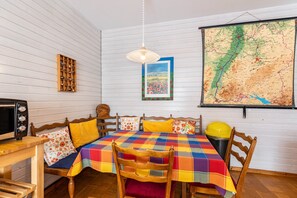 Une pièce avec un lit en bois, une table à manger avec des chaises, une carte accrochée au mur et un four à micro-ondes posé sur une table.