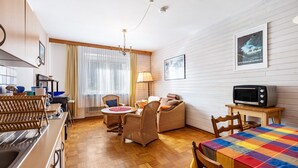 Een gezellige kamer met een eettafel, rieten meubels, een televisie en een raam met gordijnen.