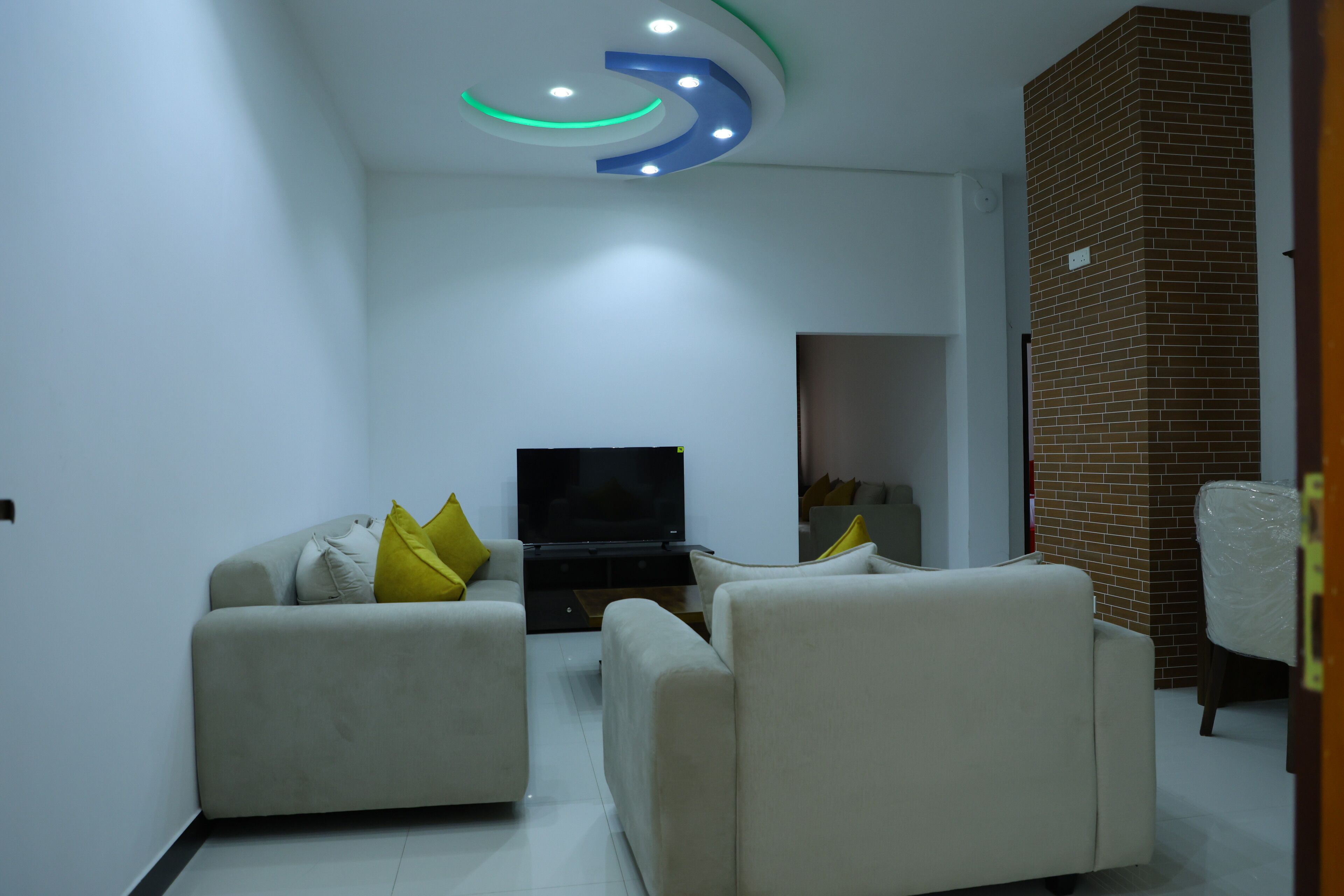 Una sala de estar moderna con un televisor de pantalla plana, dos sofás y una pared decorativa de ladrillo.