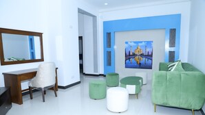 Una sala de estar moderna con un sofá verde, un escritorio de madera y un cuadro grande en la pared.