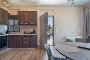 A modern kitchen with dark wooden cabinets, a built-in oven, and a dining area with a table and chairs.