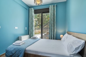 A bedroom with a bed, a nightstand, a window with curtains, and a view of a balcony.