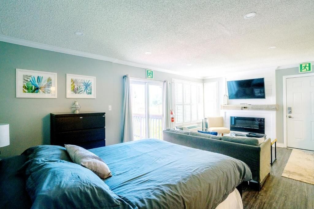 A hotel room with a bed, a dresser, a television, and a balcony.