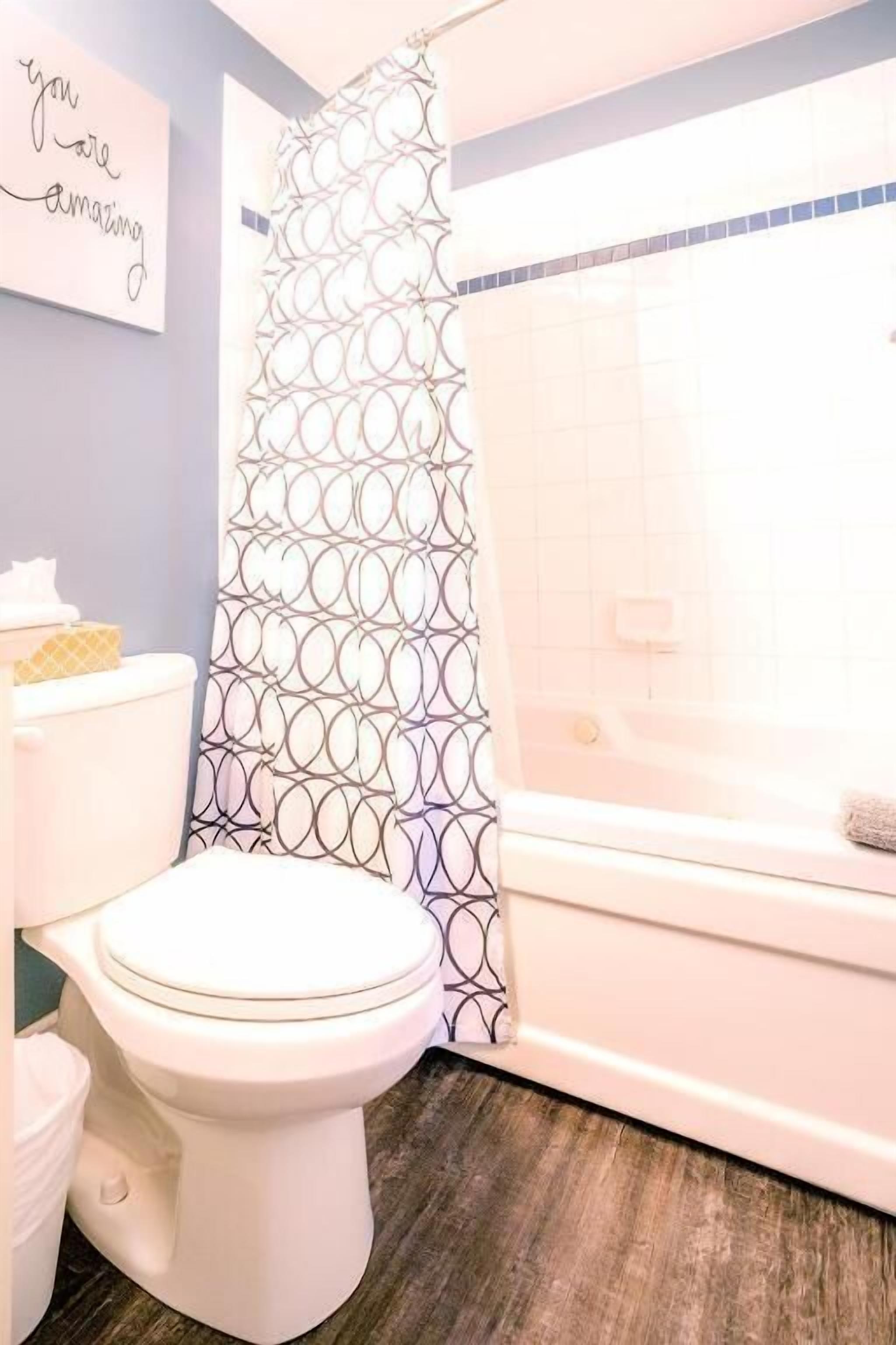 Un baño con inodoro, cortina de ducha con diseño circular y bañera.