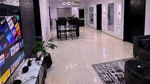 Una hall d'albergo moderna con area ristorazione, banco reception e un grande schermo piatto.