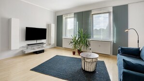 A modern living room with a flat-screen TV, a round coffee table, a sofa, and a potted plant. - Holiday Apartment 'Spree - Oase' in Spremberg (Spremberg)
