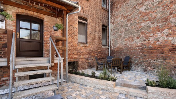 A brick building with a wooden door, outdoor seating, and a stone staircase. - Holiday Apartment 'Spree - Oase' in Spremberg (Spremberg)