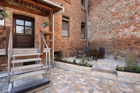 A brick building with a wooden door, outdoor seating, and a stone staircase.. Holiday Apartment 'Spree - Oase' in Spremberg