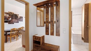 A room with a wooden cabinet, a dining area with chairs, and a tiled floor. - Holiday Apartment 'Spree - Oase' in Spremberg (Spremberg)